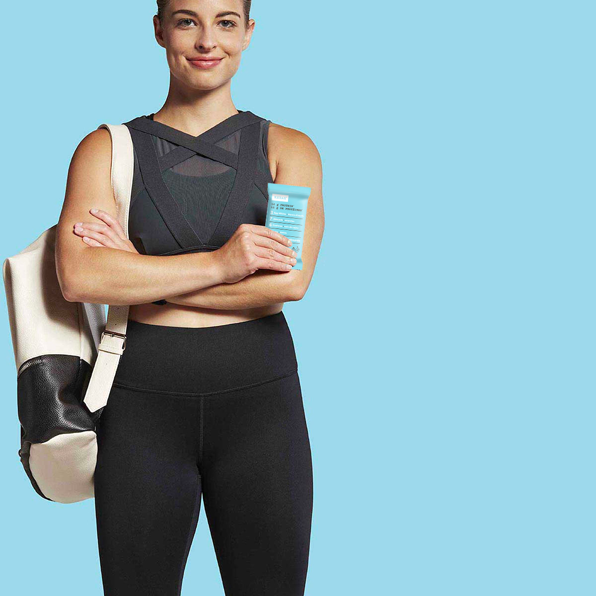 A woman in workout gear holding a Vanilla Almond RX Bar