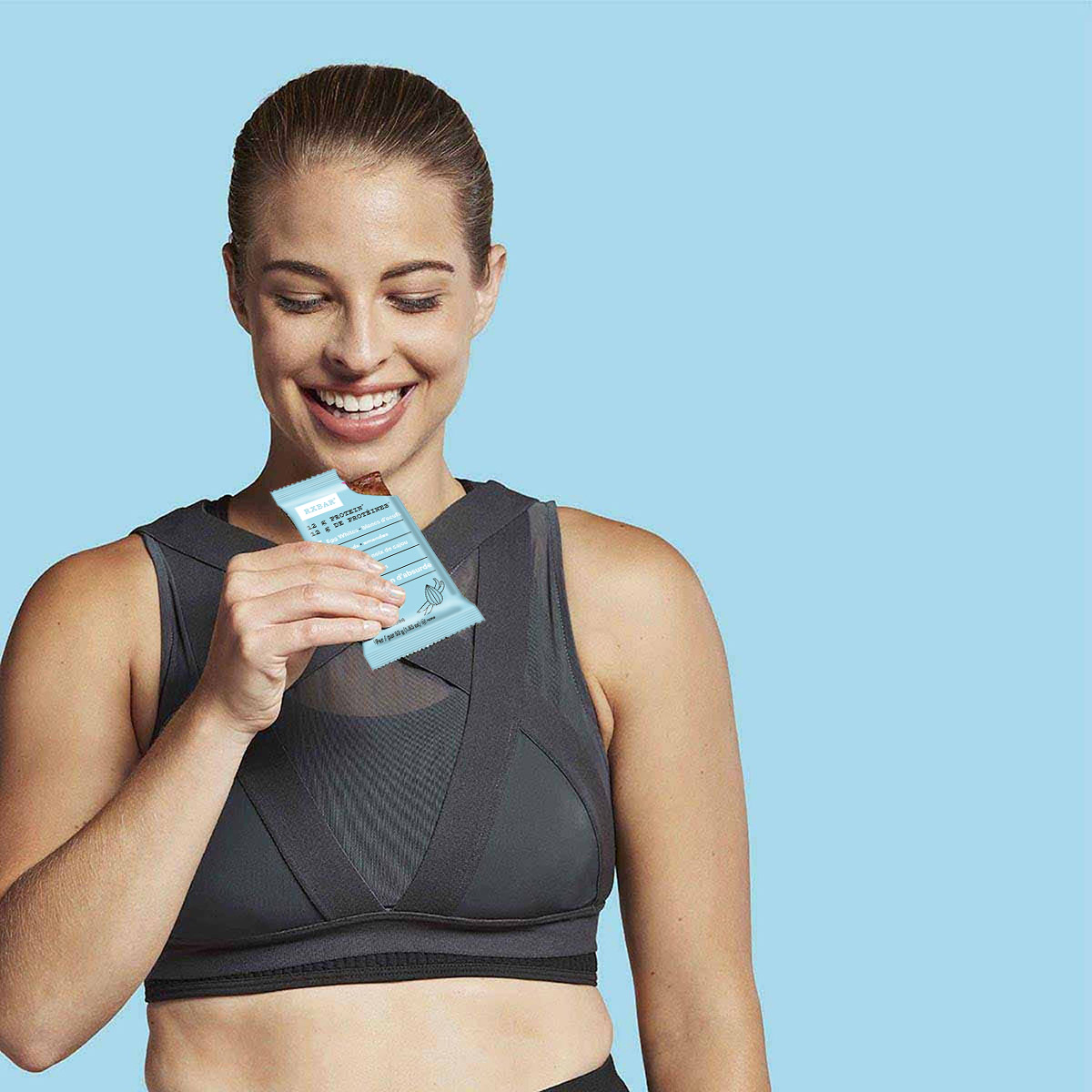 A woman in workout gear holding a Vanilla Almond RX Bar